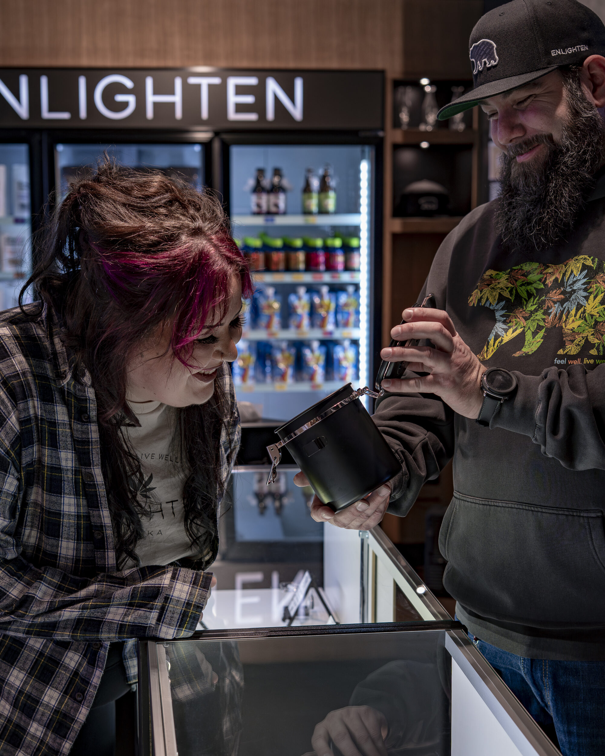 Enlighten Alaska's budtender showing off flower to a customer in Enlighten's Anchorage Old Seward Location