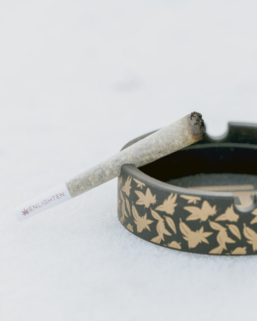 A lit Enlighten Alaska preroll resting on an ash tray