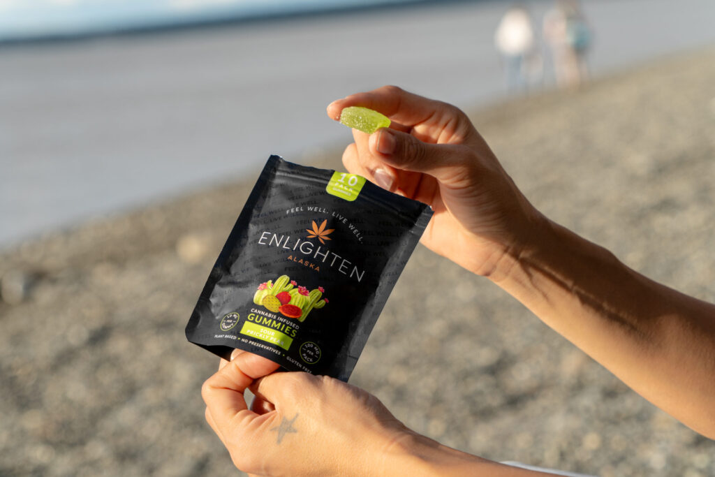 Hands holding a Sour Prickly Pear gummy cannabis edible from Enlighten Alaska