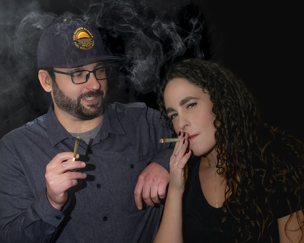 Enlighten Alaska CEO Evan Levinton and co-owner CAO Leah Levinton smoking prerolls together against a black background