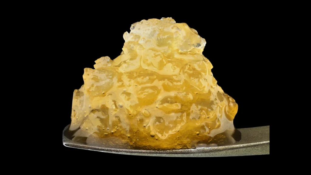 Cannabis sugar wax concentrate with a crumbly, crystallized texture and golden color, a flavored solvent-extracted dab option